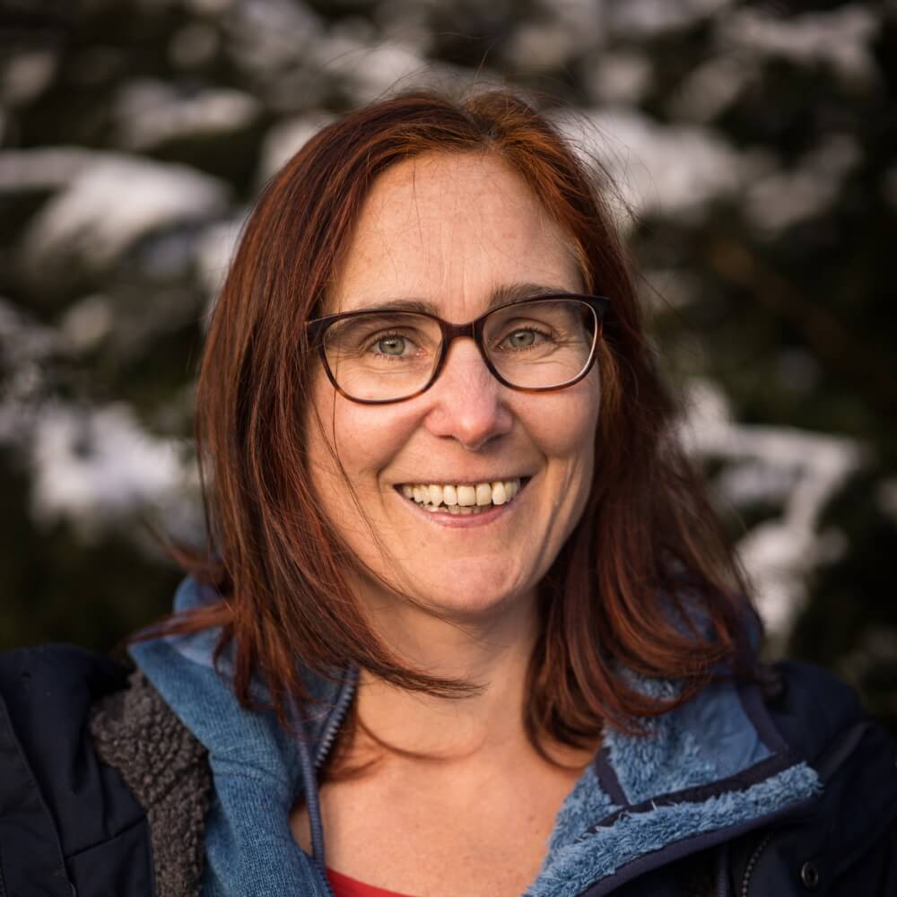 Dorina Hoppmann, Natur- und Wildnispädagogin, vor verschneiten Zweigen